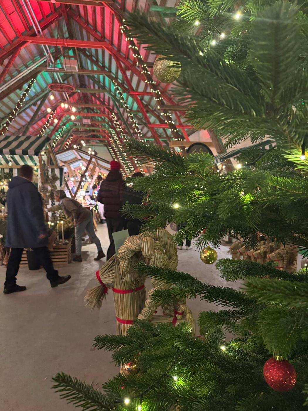 Marknadsstånd med ljusslingor och julgran under logens takstolar
