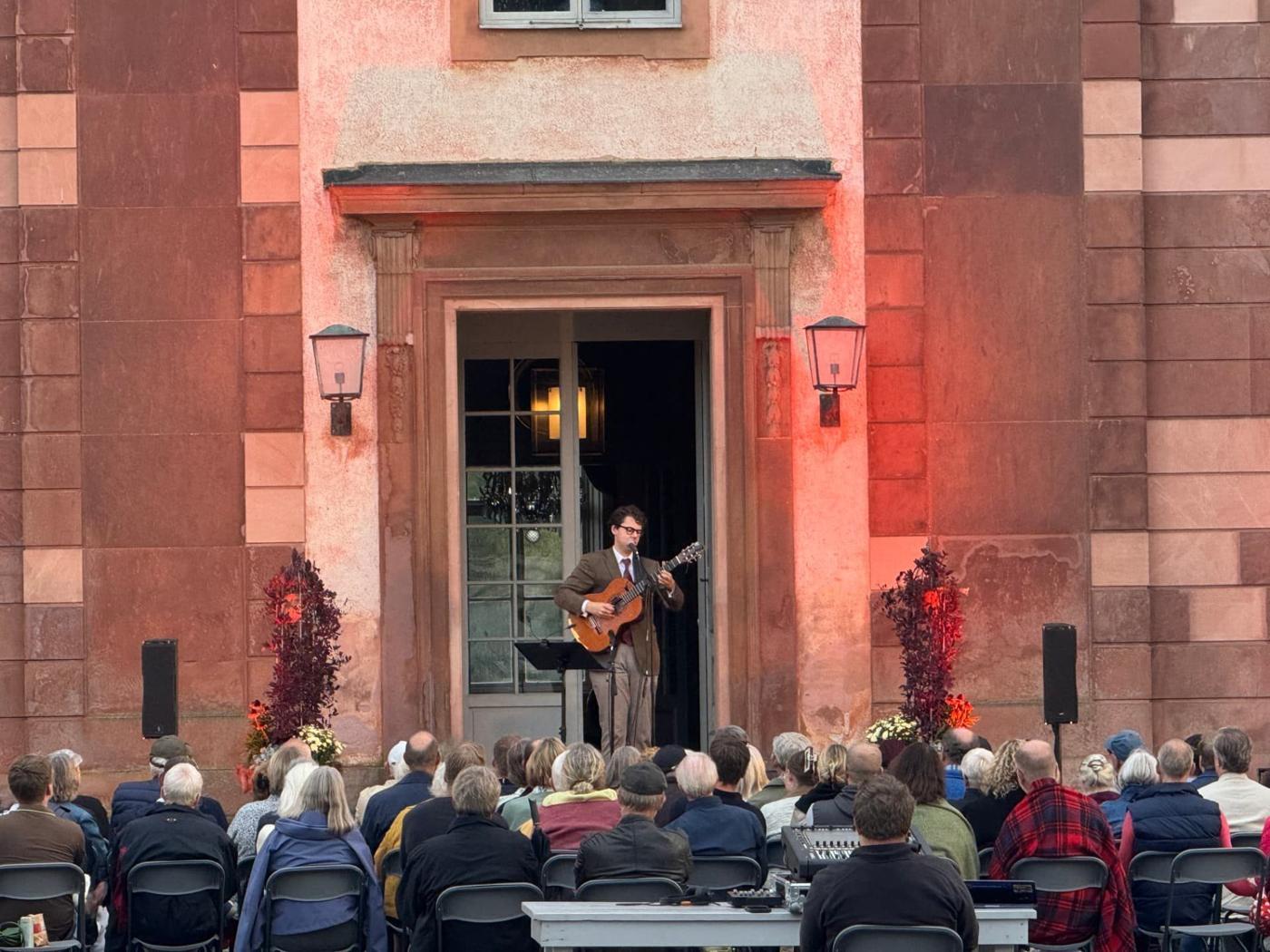 William Sundman Sääf med gitarr uppträder i den upplysta portalen inför publik